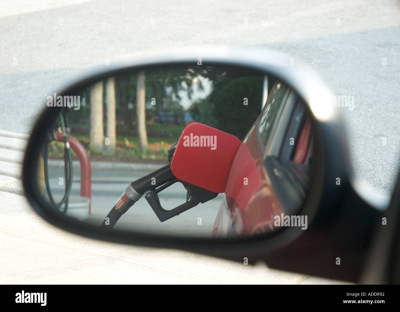 Rear view mirror reflection of a gasoline pump filling a car s fuel tank Stock Photo