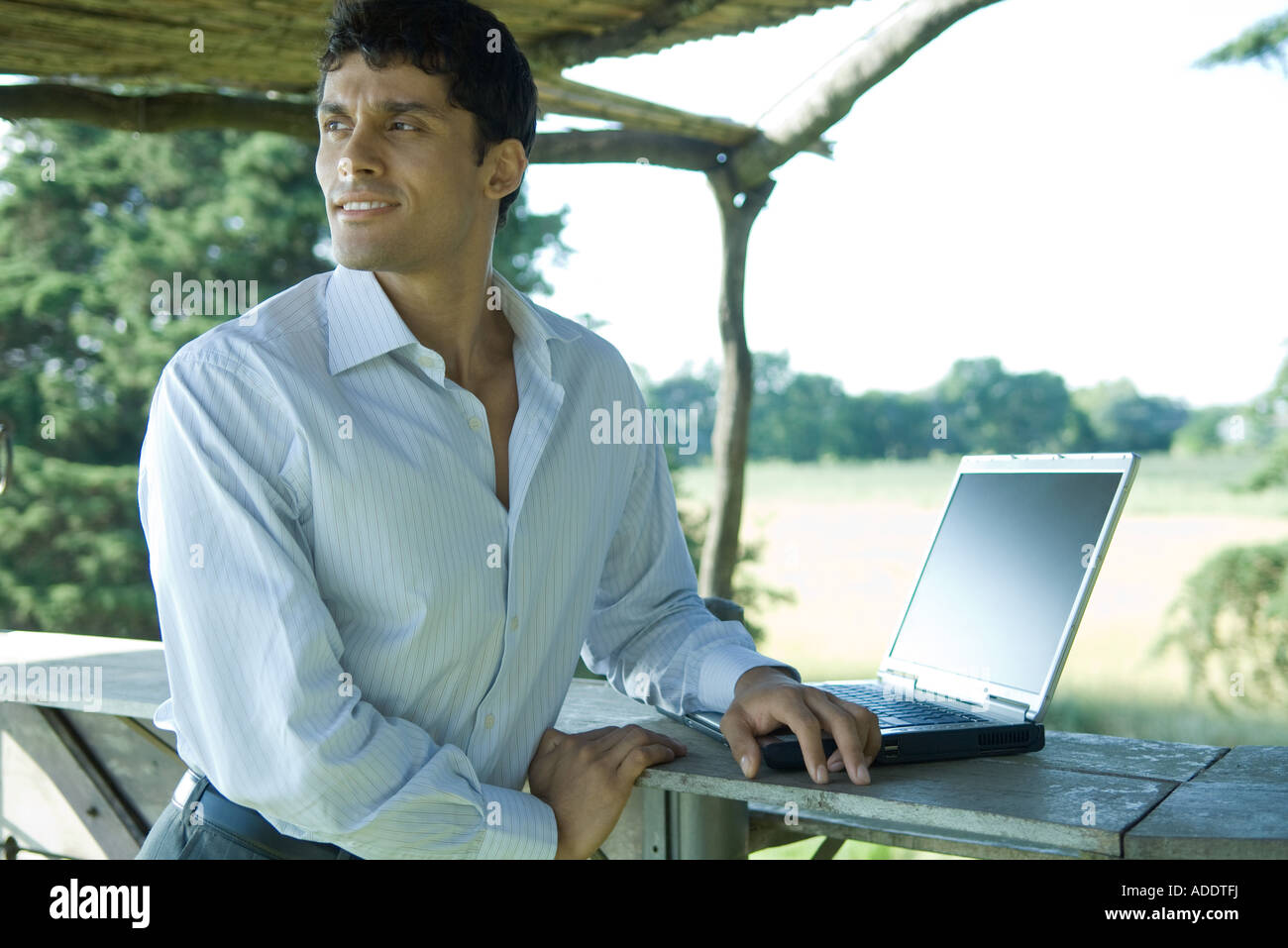 Businessman using laptop outdoors, looking over shoulder Stock Photo