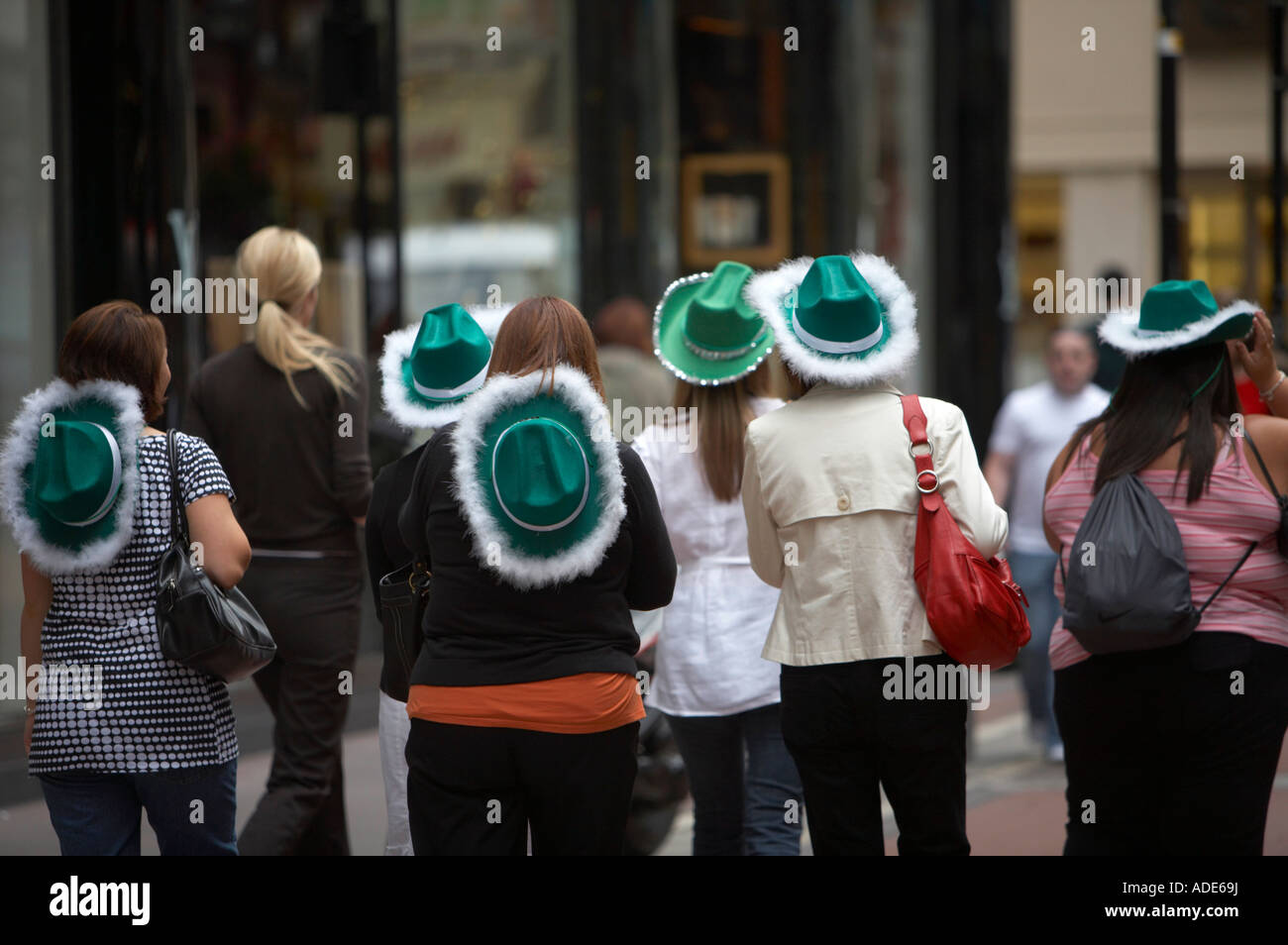 hen party of english women wearing green and white cowboy hats walks through shopping area of dublin Stock Photo Alamy