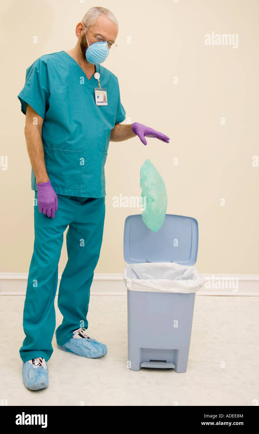 Male healthcare worker places disposables into trash Stock Photo