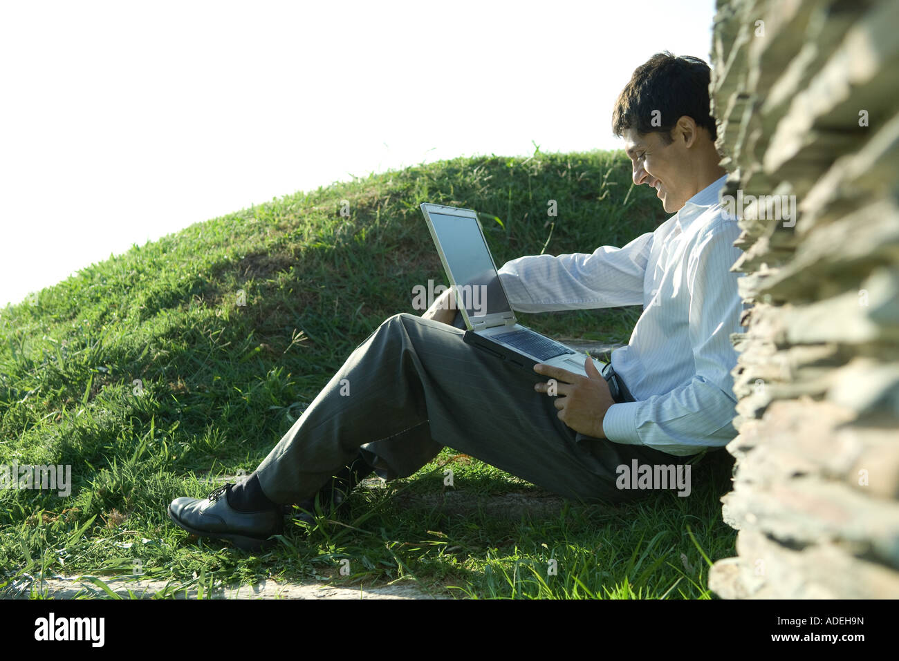 Businessman sitting outdoors, using laptop Stock Photo - Alamy