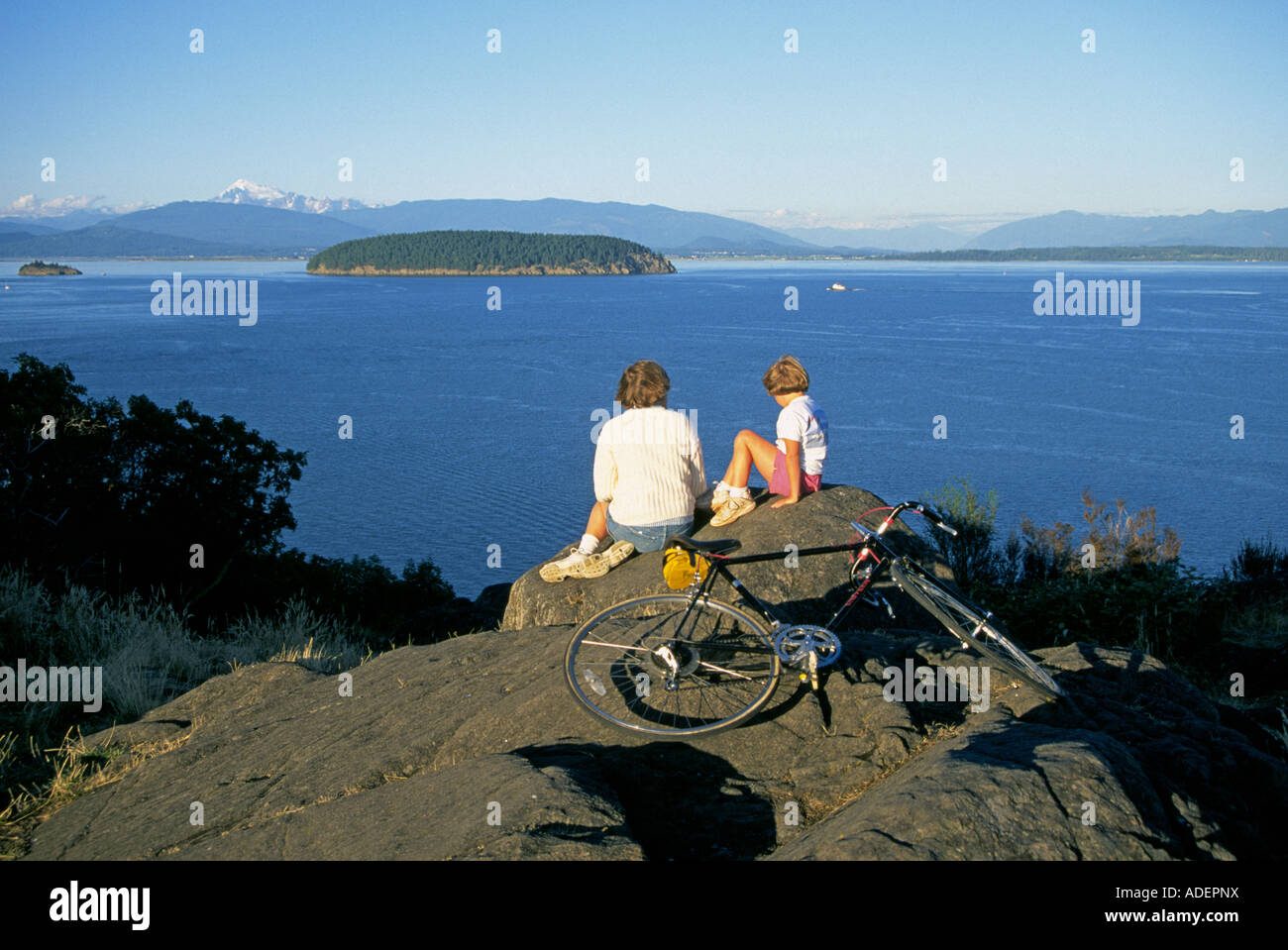 A mother and daughter on bicycles look for whales in Puget Sound in the San Juan Islands, Washington. Stock Photo