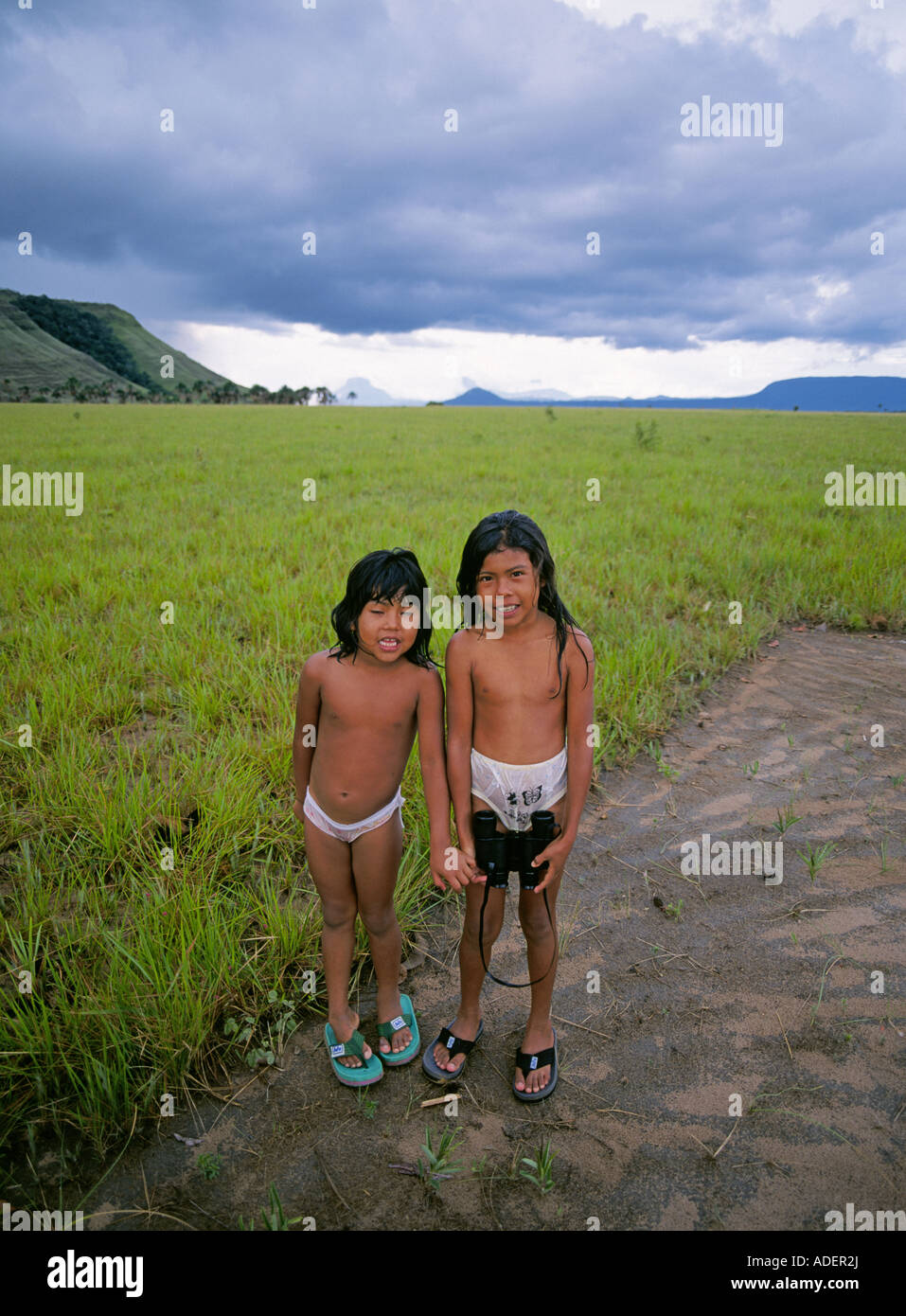 Two young Pemon Indian girls and view of the mesas known as tepuis in the Gran Sabana region of Venezuela. Stock Photo