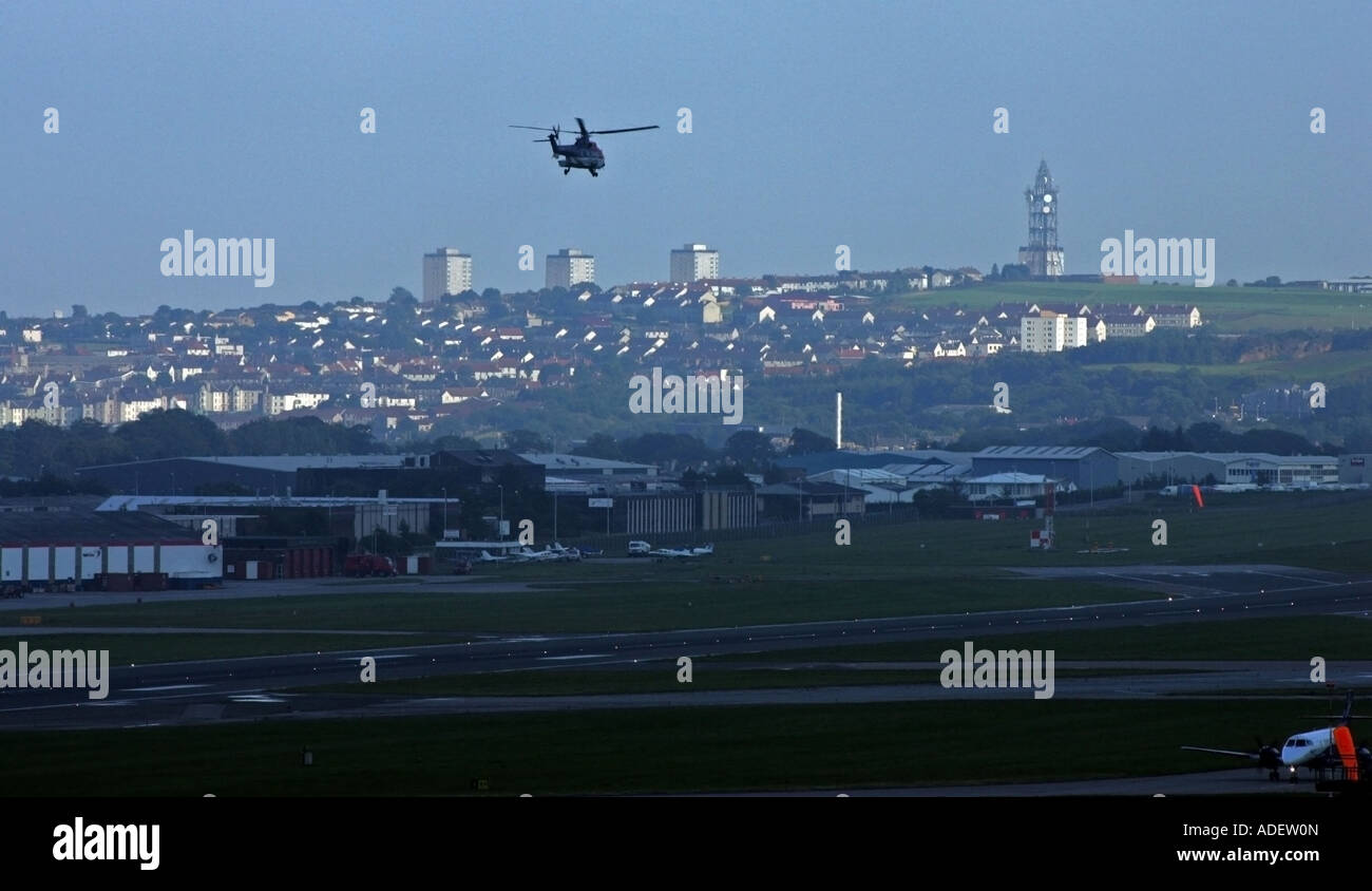 Helicopter takes off from Aberdeen Airport in the evening with the city in the background Stock Photo