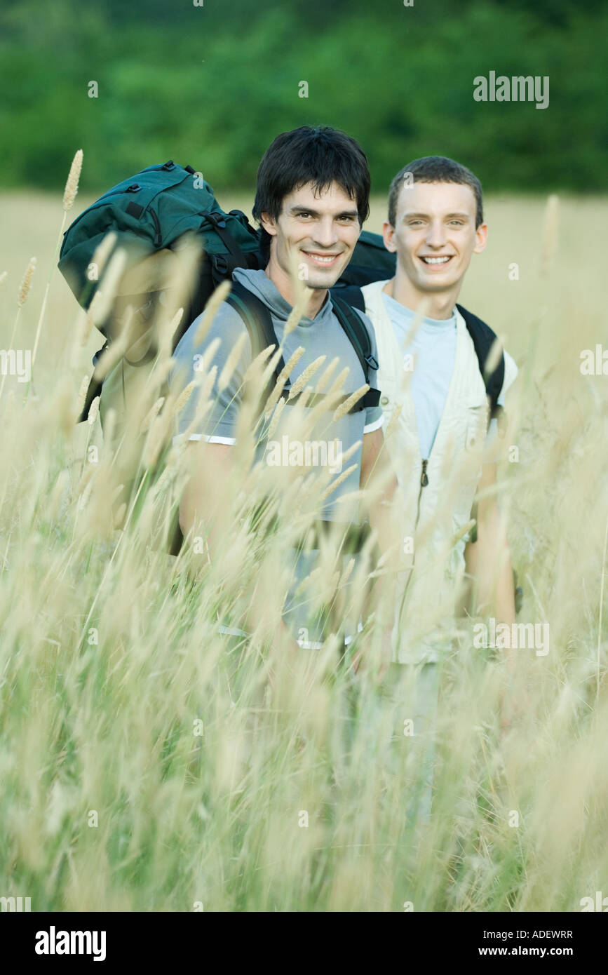 Two hikers standing in field, smiling at camera Stock Photo - Alamy