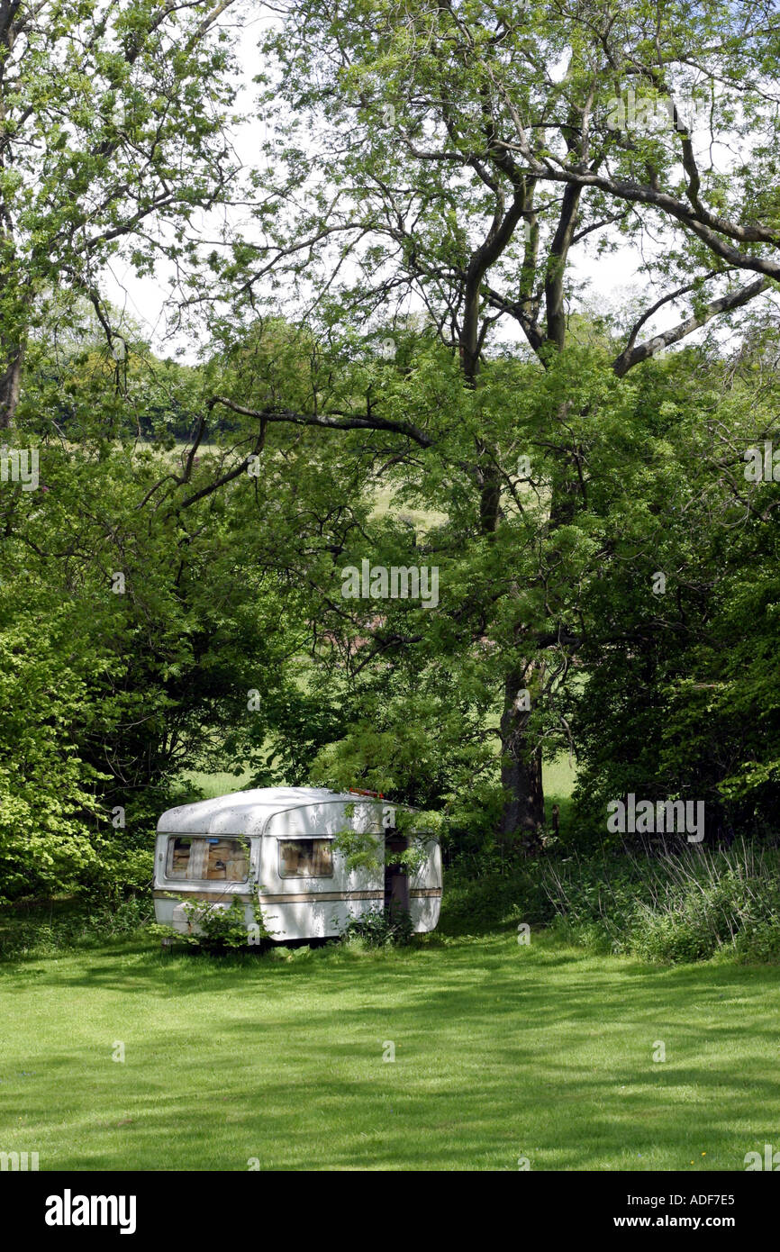 Old delapidated caravan in the woods being used for storage Stock Photo