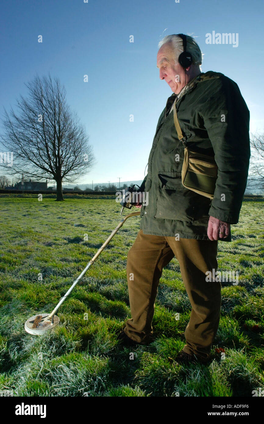 Metal detector searching farmland on a cold frosty winters morning in the West Country England UK Stock Photo