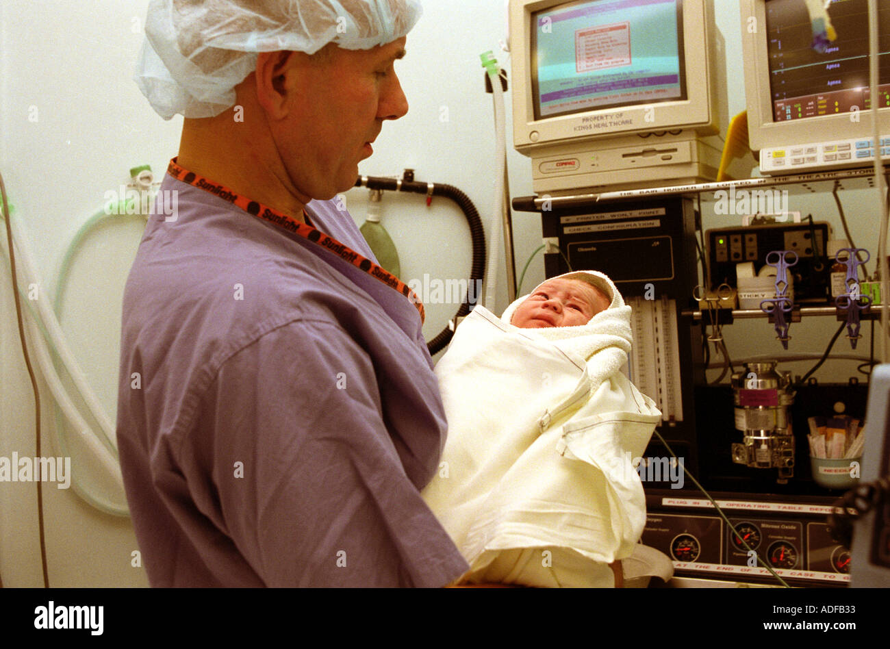 Father holding his newborn baby in operating theatre directly after forceps delivery. Stock Photo