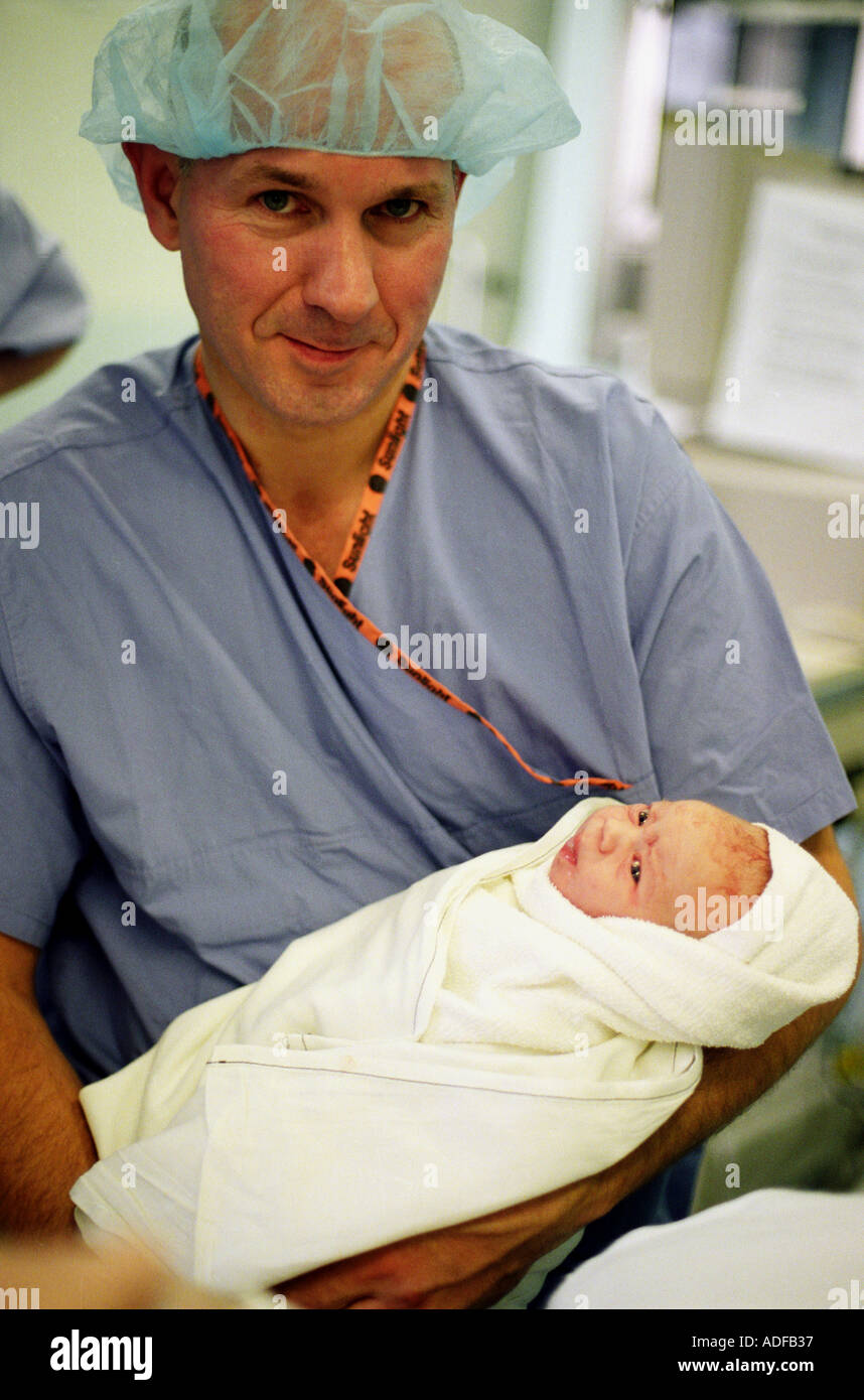 Father with newborn baby following forceps delivery in operating theatre. Stock Photo