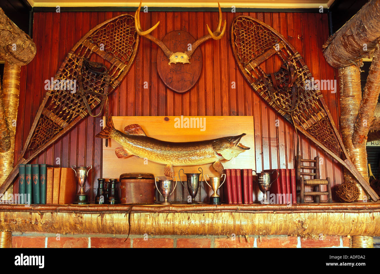 USA,New York, Lake Placid, Lake Placid Lodge,snowshoes fish trophies and books decorating a rustic mantle Stock Photo