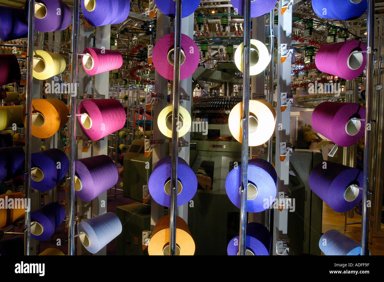 Commercial knitting machine with coloured yarns on display at trade