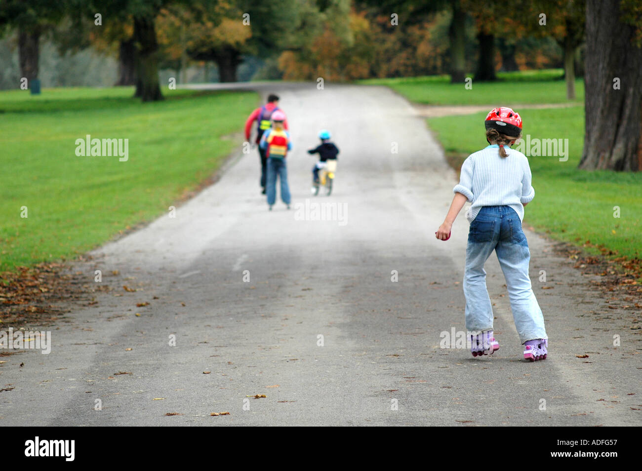 a family having a day out at the park, children rollerblading and cycling Stock Photo