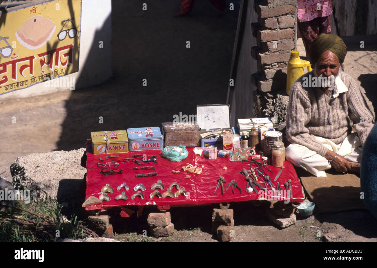 Indian dentist displaying the tools of his trade ,pliers ,spare teeth ,etc ,In Chitral,India Stock Photo