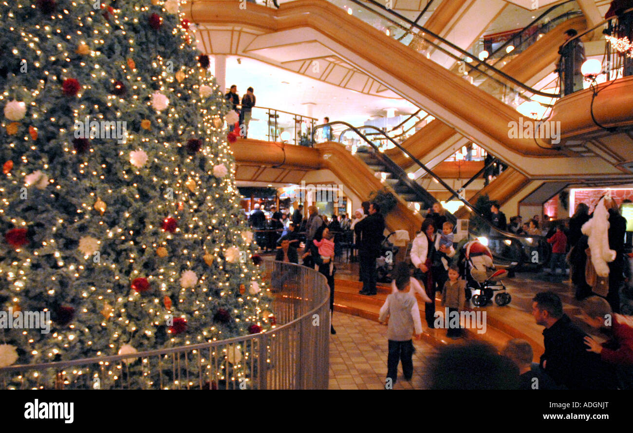 People Sitting Around Christmas Tree. Princes Square Shopping Centre, Glasgow.Scotland. Christmas Eve December 2006 Stock Photo
