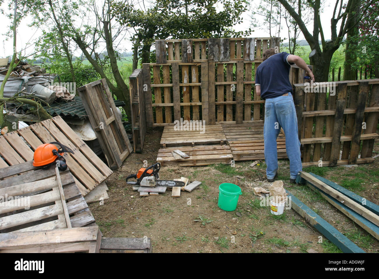 Man Building A Log Shed Using Reclaimed Pallets Woodshed To Be Used