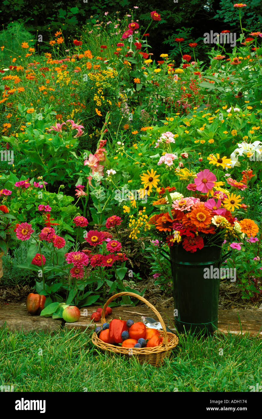 Flowers in metal vase along with fruit and vegetables gathered by