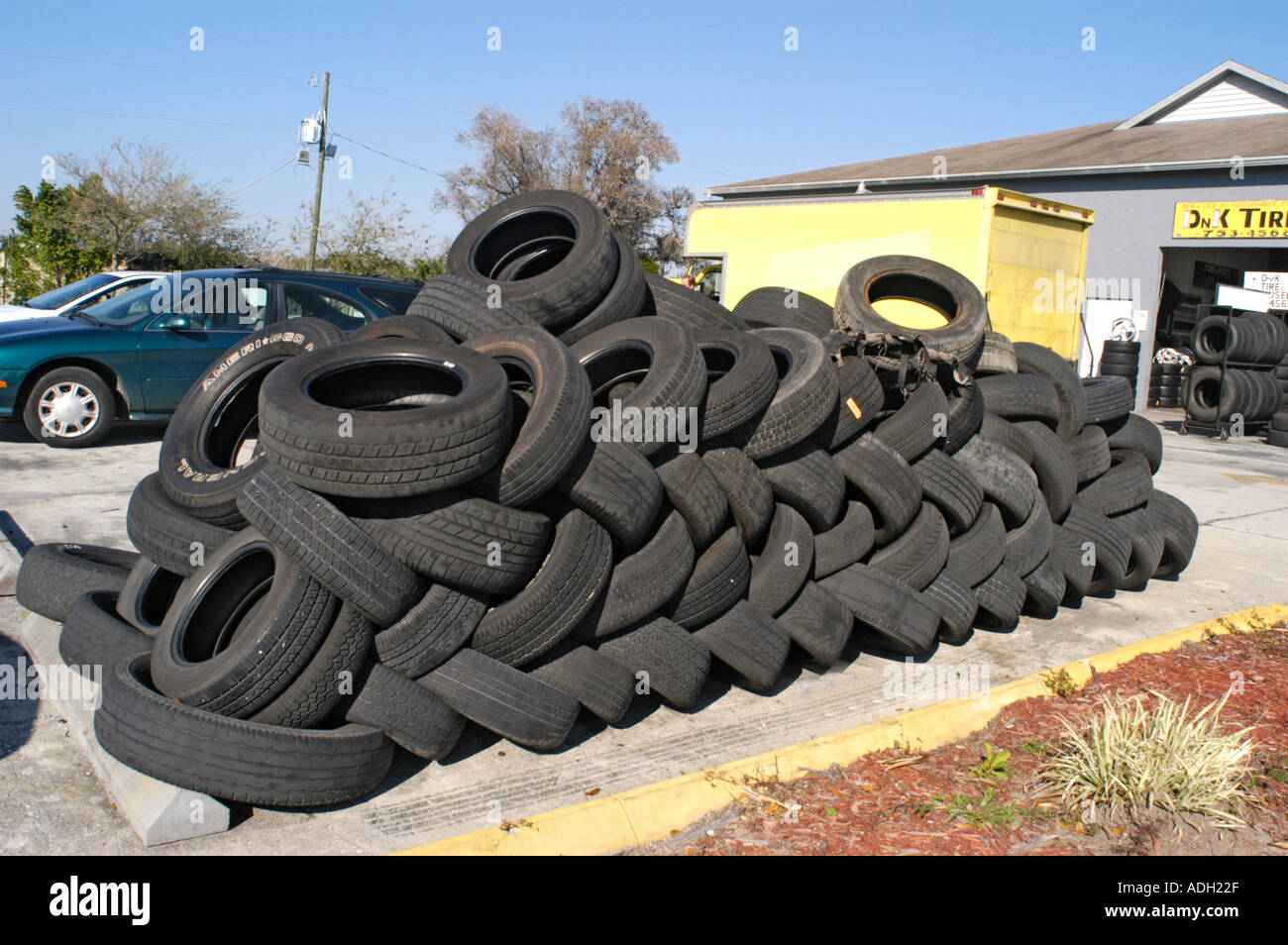 Used tires stacked behind a tire store waiting to be put to some use