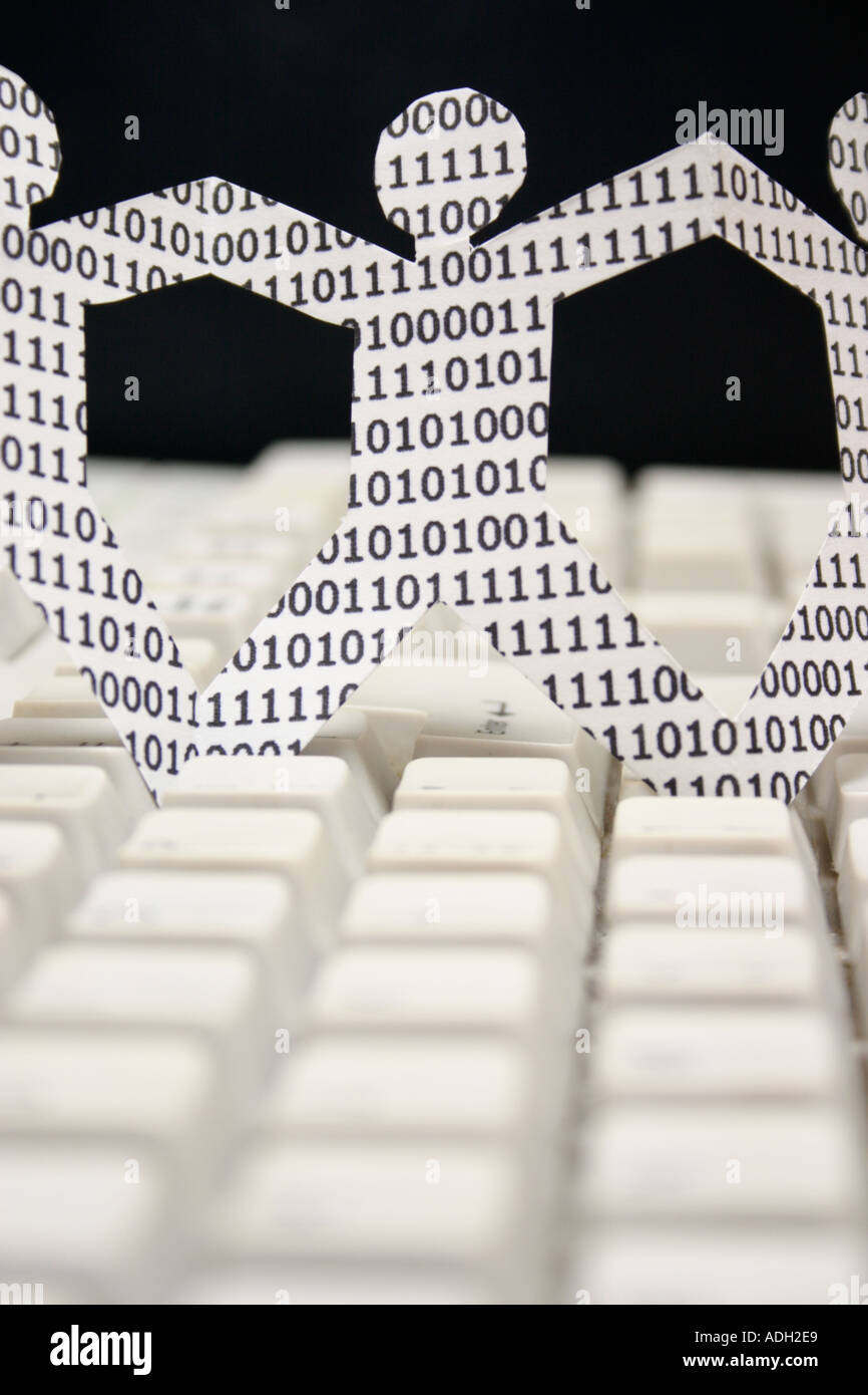 symbolic knowledge workers in the information technology industry paper dolls with binary numbers on keyboard Stock Photo