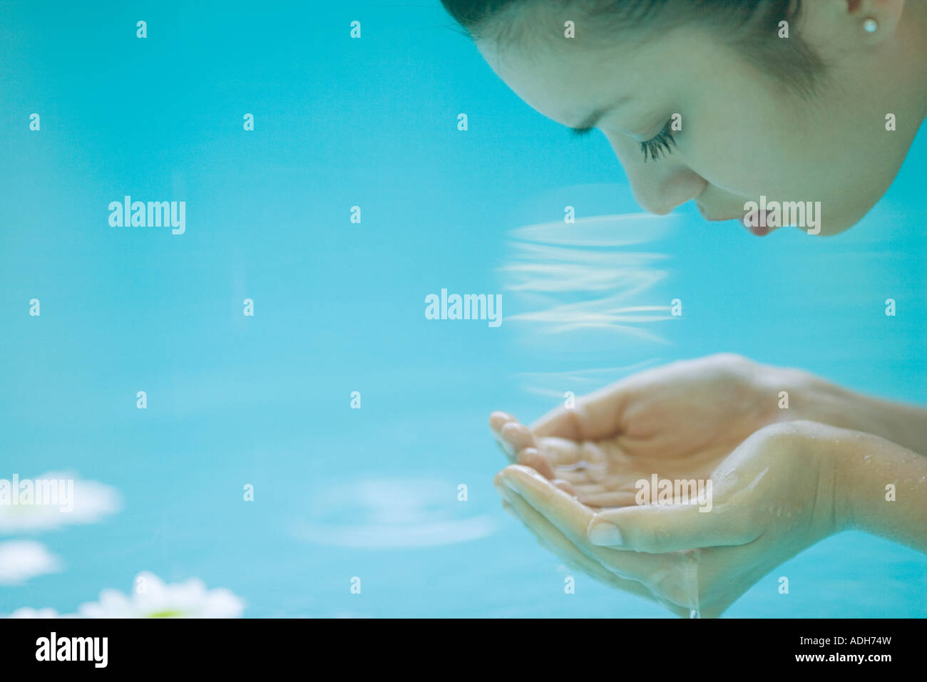 Young woman bending over water, cupping hands, close-up Stock Photo