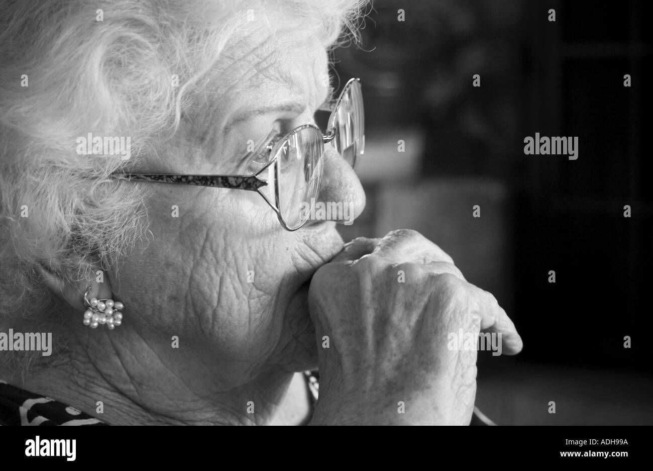 Black and white photo of a pensive, elderly woman. Stock Photo
