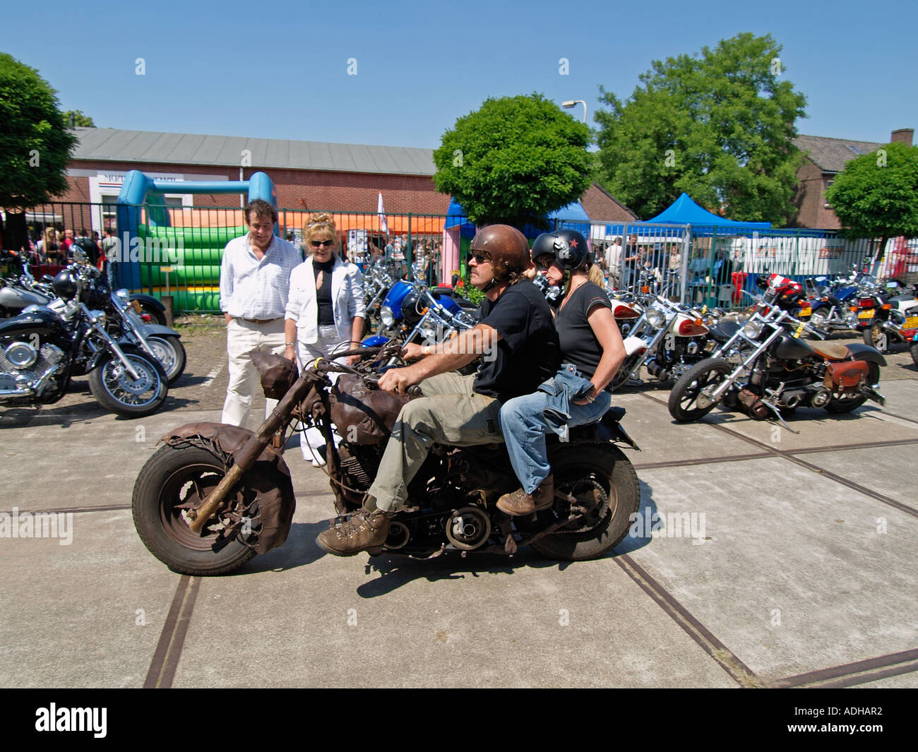 Couple riding their rat bike style custom Harley Davidson chopper with other couple watching them Breda the Netherlands Stock Photo