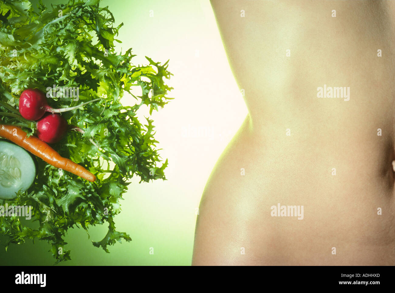 Close up of nude female torso with salad Stock Photo