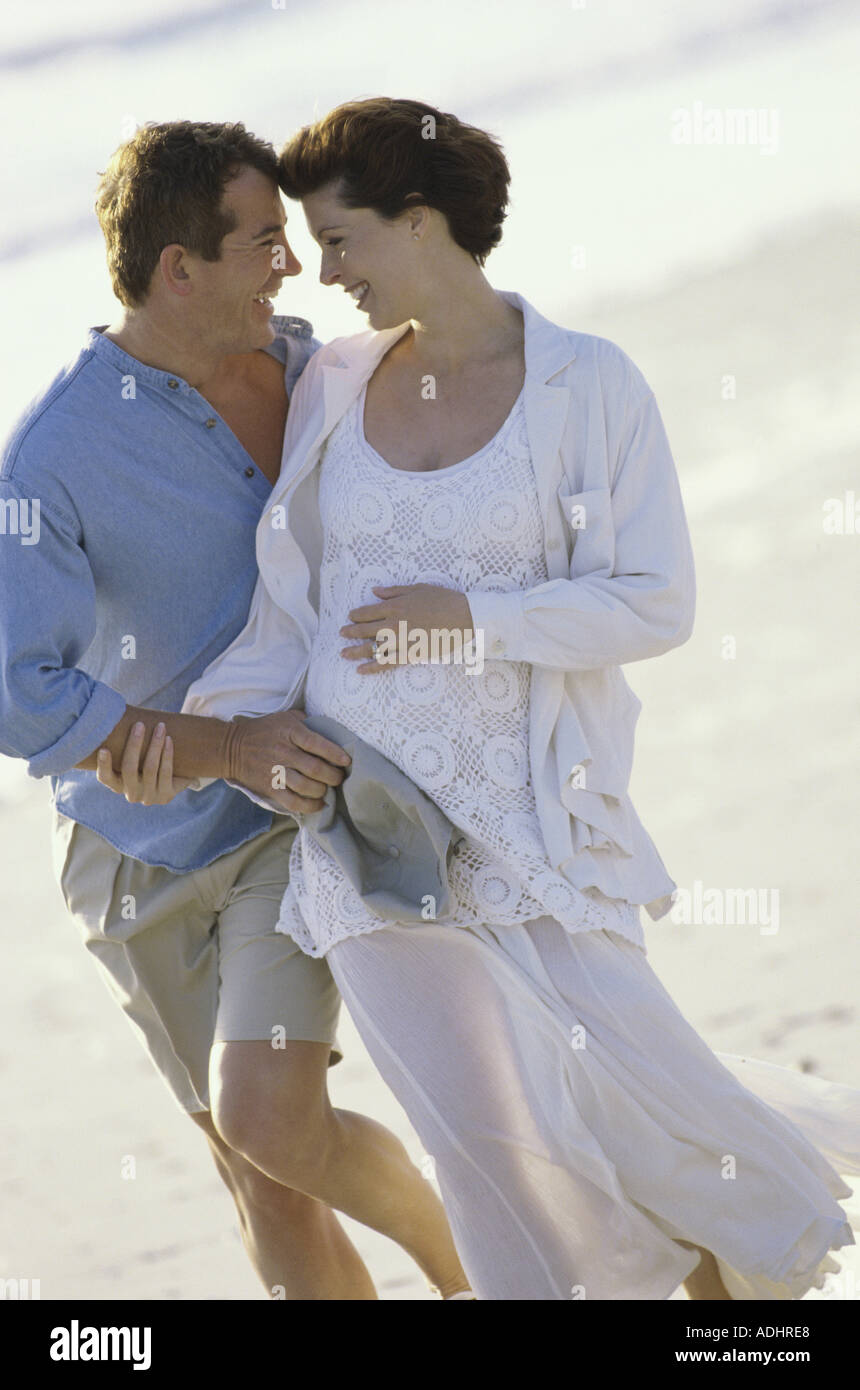 Husband walking on the beach with his pregnant wife Stock Photo