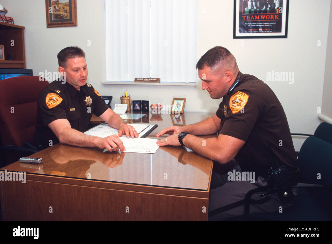 Sergeant and Captain at desk looking through paperwork. Sheriff's