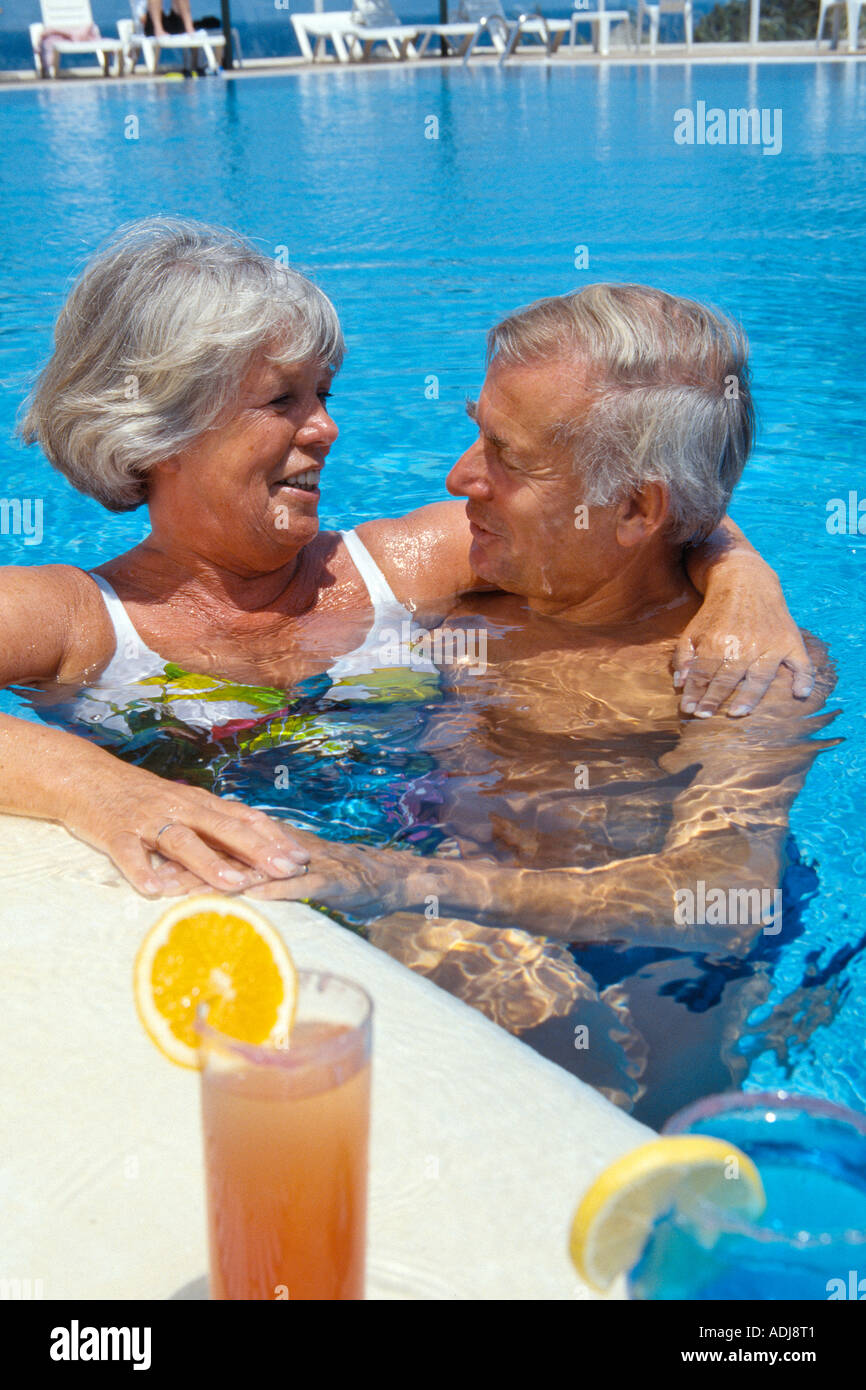 Spanien Ibiza Seniorenpaar im Pool mit Cocktails Umarmung Stock Photo