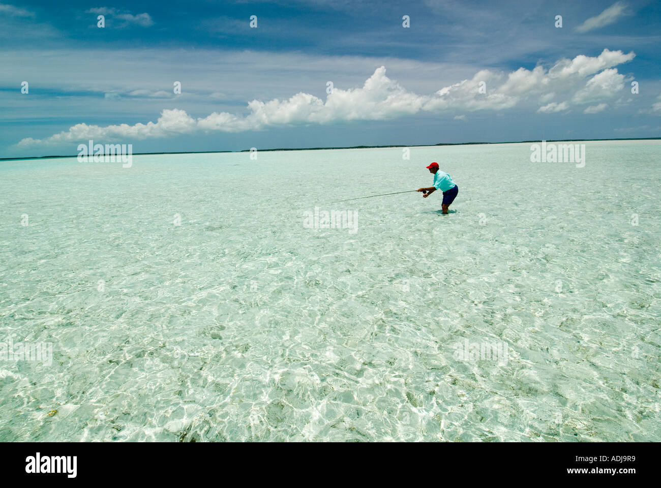 GREATER EXUMA BAHAMA Fly fisherman wading in emerald green sea casting for Bonefish in flats Atlantic Ocean Stock Photo