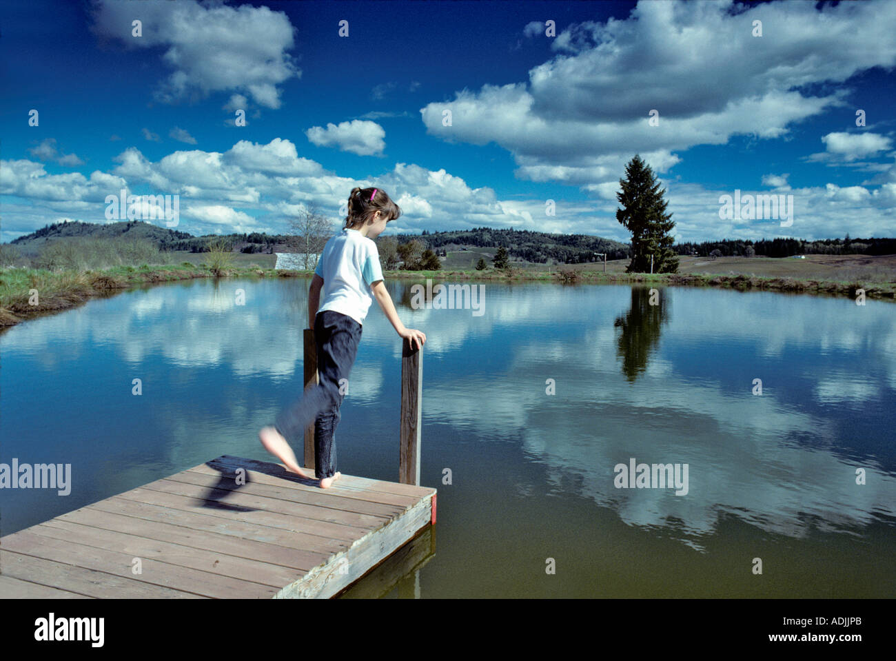 Young girl on dock at pond Near Alpine Oregon Stock Photo