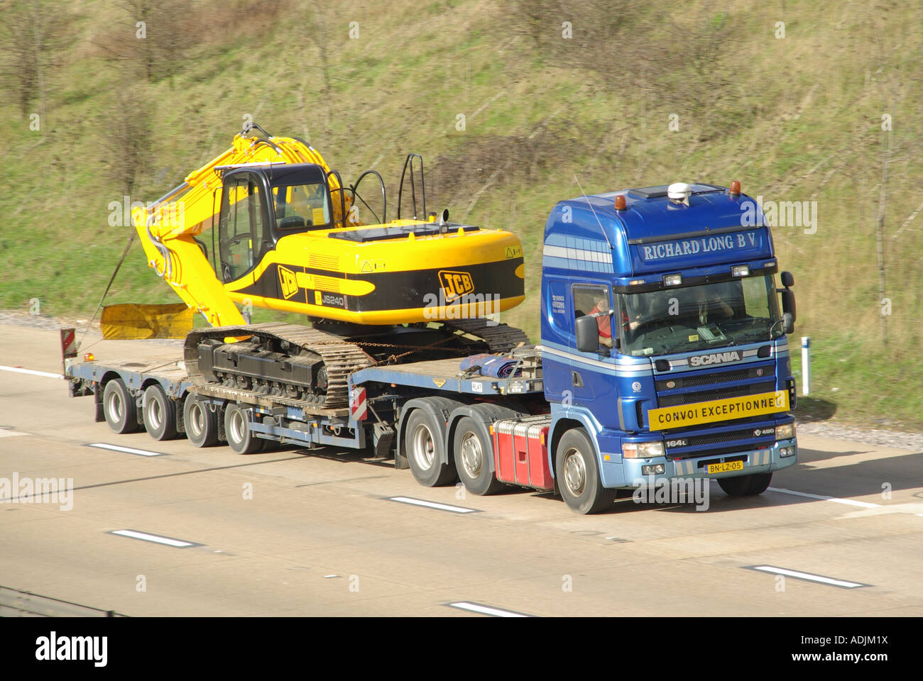 Netherlands NL country code on Scania 164L 480 lorry truck & low loader trailer JCB JS240 excavator wide load CONVOI EXCEPTIONNEL on UK motorway road Stock Photo