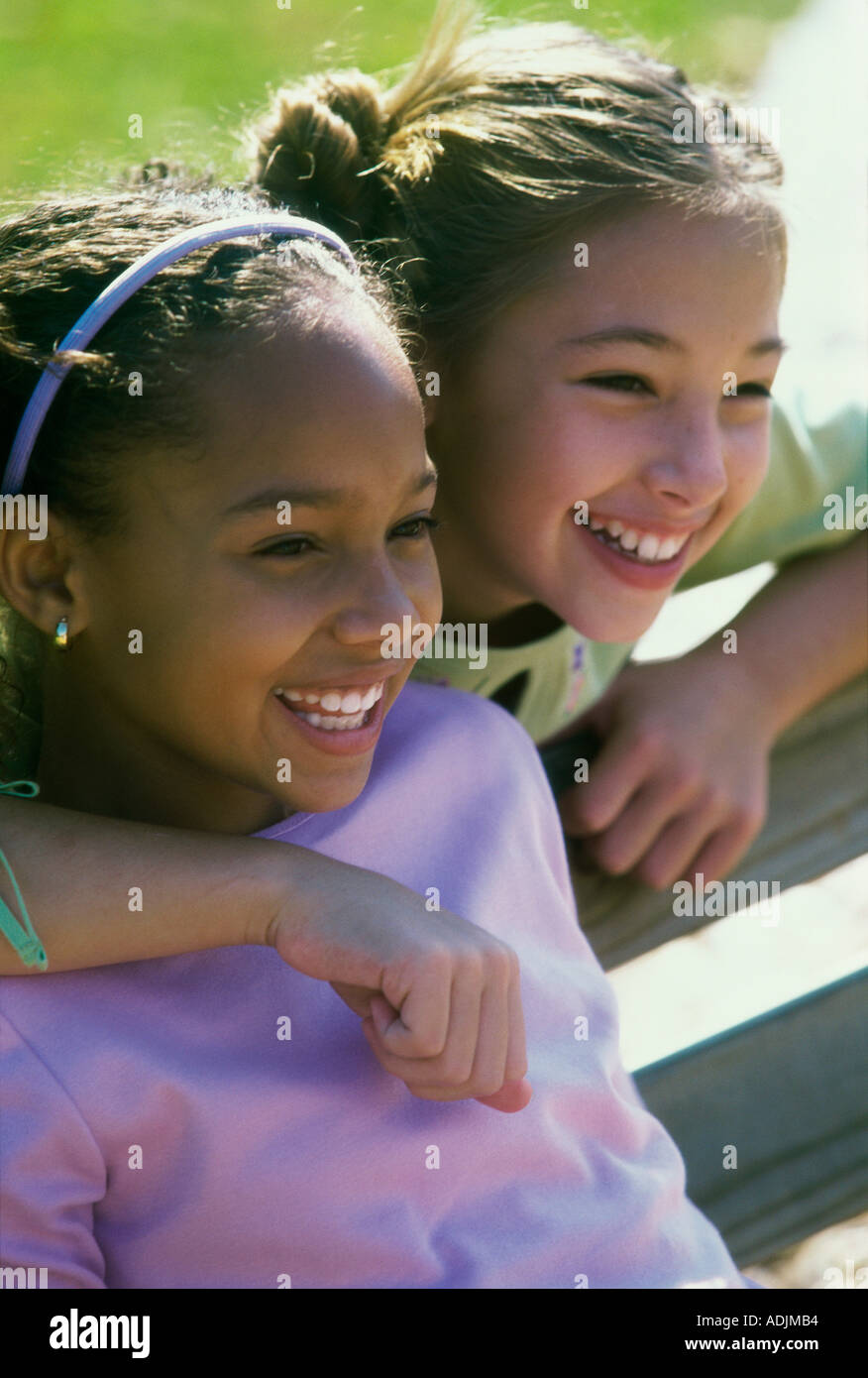 Two girls sitting on a bench smiling Stock Photo - Alamy