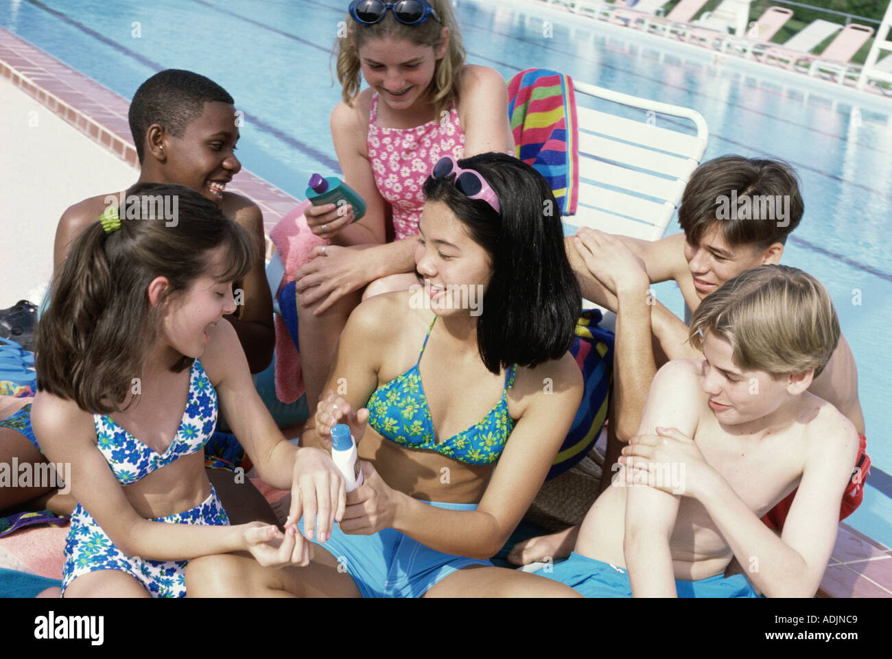 Group of teenagers sitting beside a swimming pool Stock Photo - Alamy