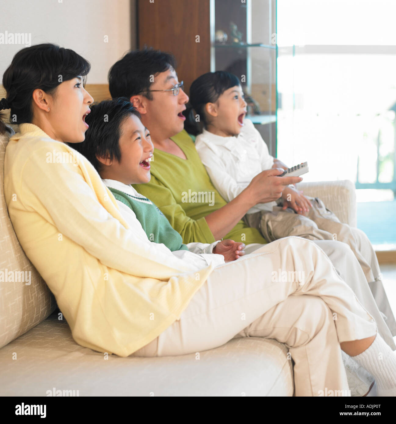 A Korean family is watching a TV and surprised in the living room Stock