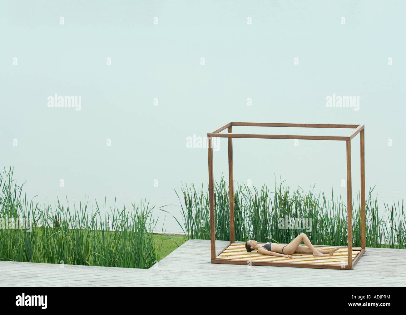 Young woman lying in square structure near body of water Stock Photo ...