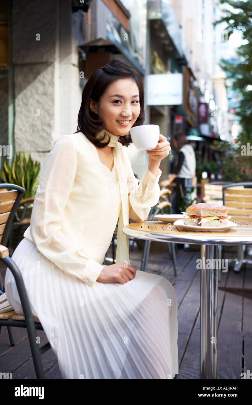 A woman is sitting on the chair and drinking coffee with a smile Stock ...