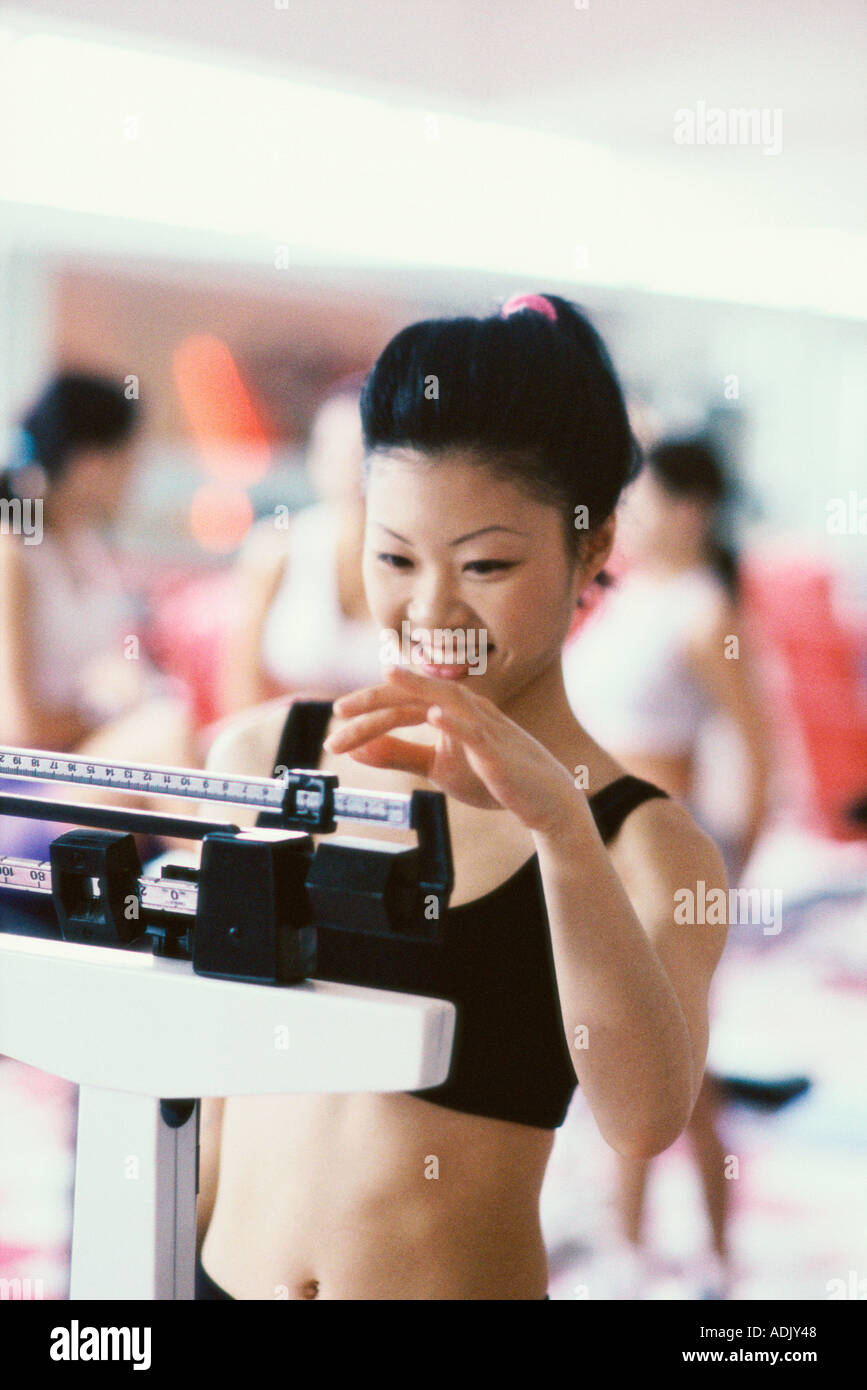 Young woman standing on a weight scale Stock Photo