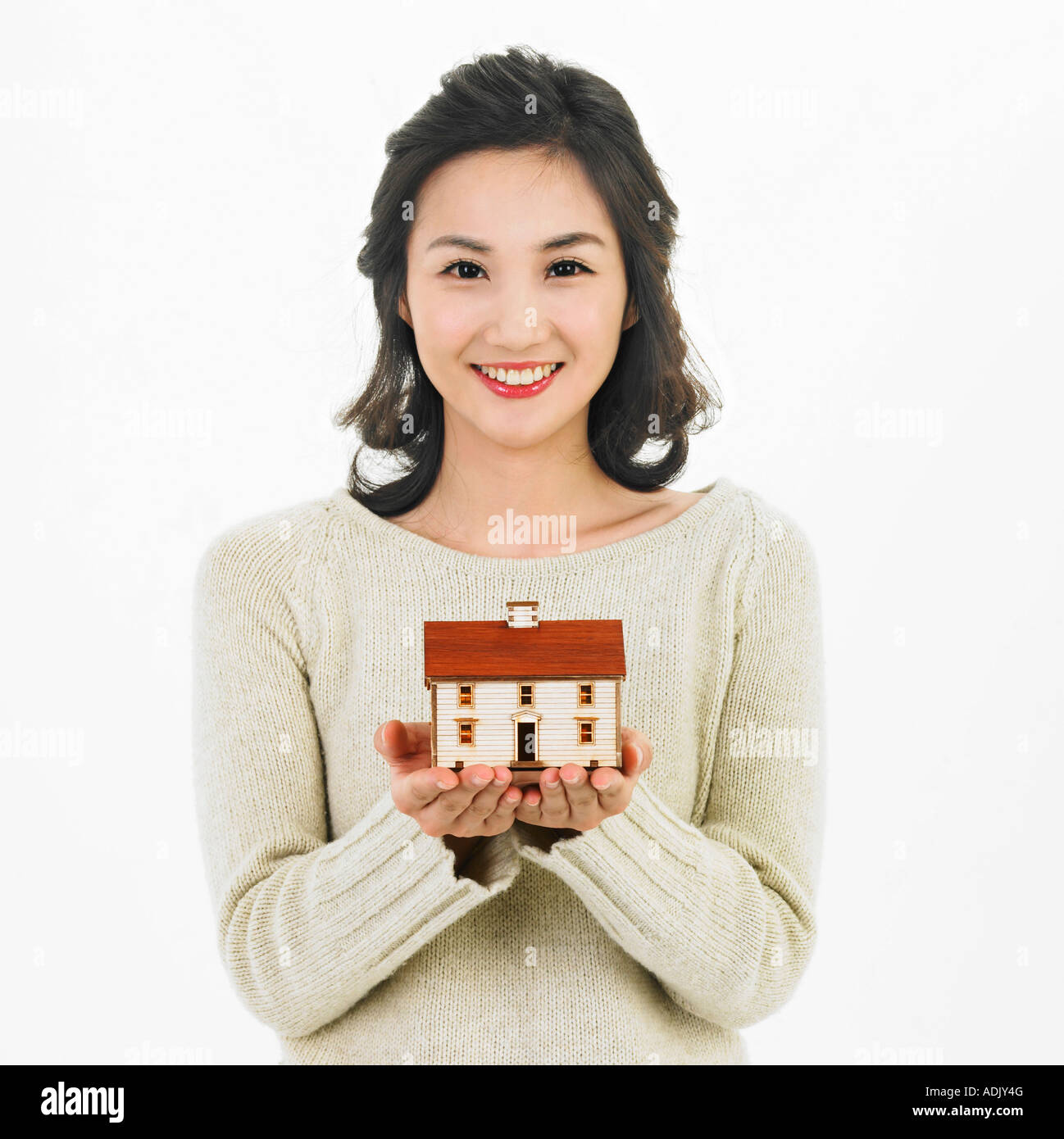 A smiling woman resting a model house on her hands Stock Photo - Alamy