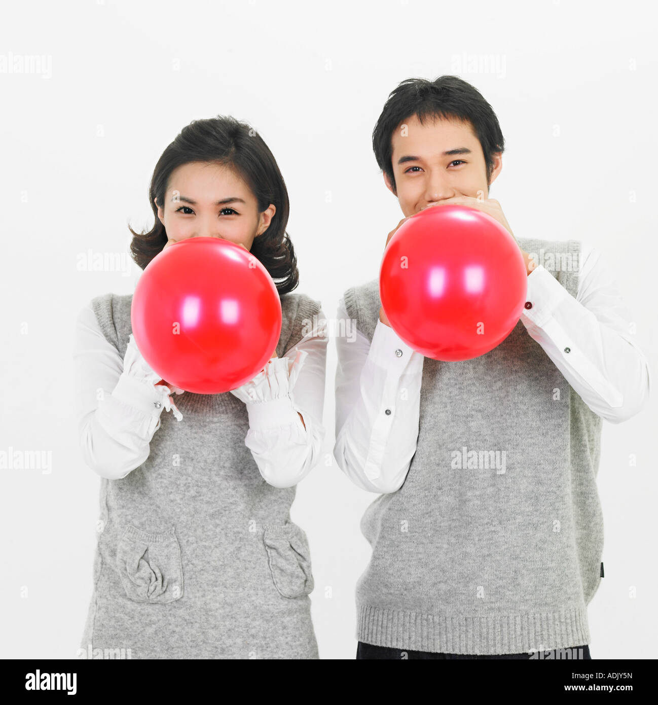 A smiling couple blowing a heart balloon happily Stock Photo - Alamy