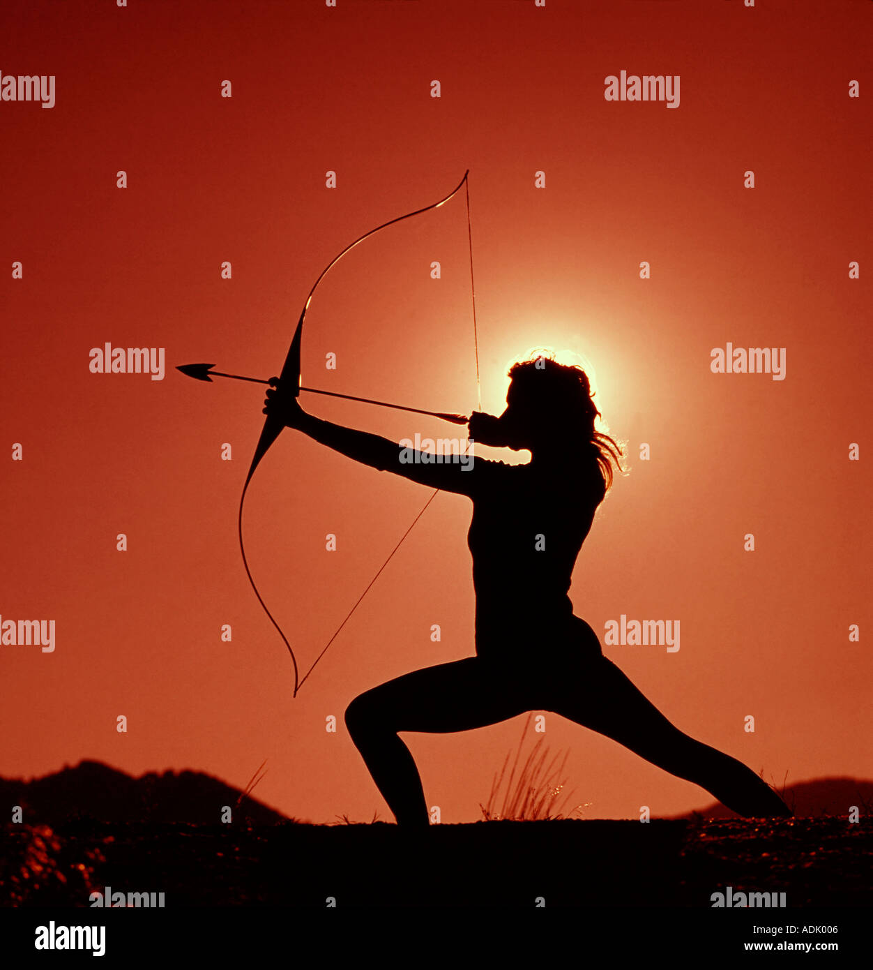 sunset silhouette of dramatic and agressive pose of young woman aiming ADK006