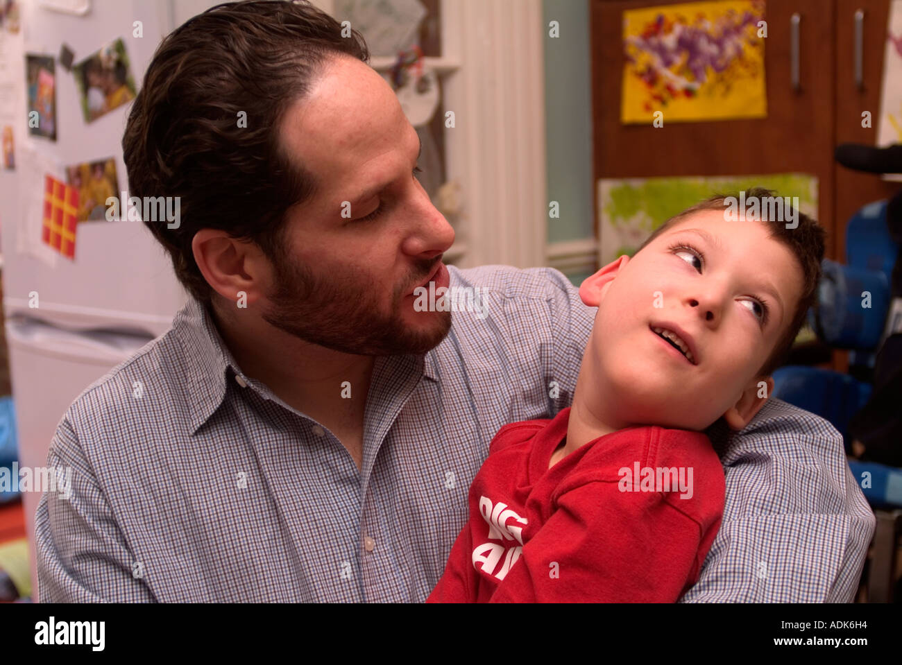 Father at home cradling his disabled son in his arms, London, UK Stock