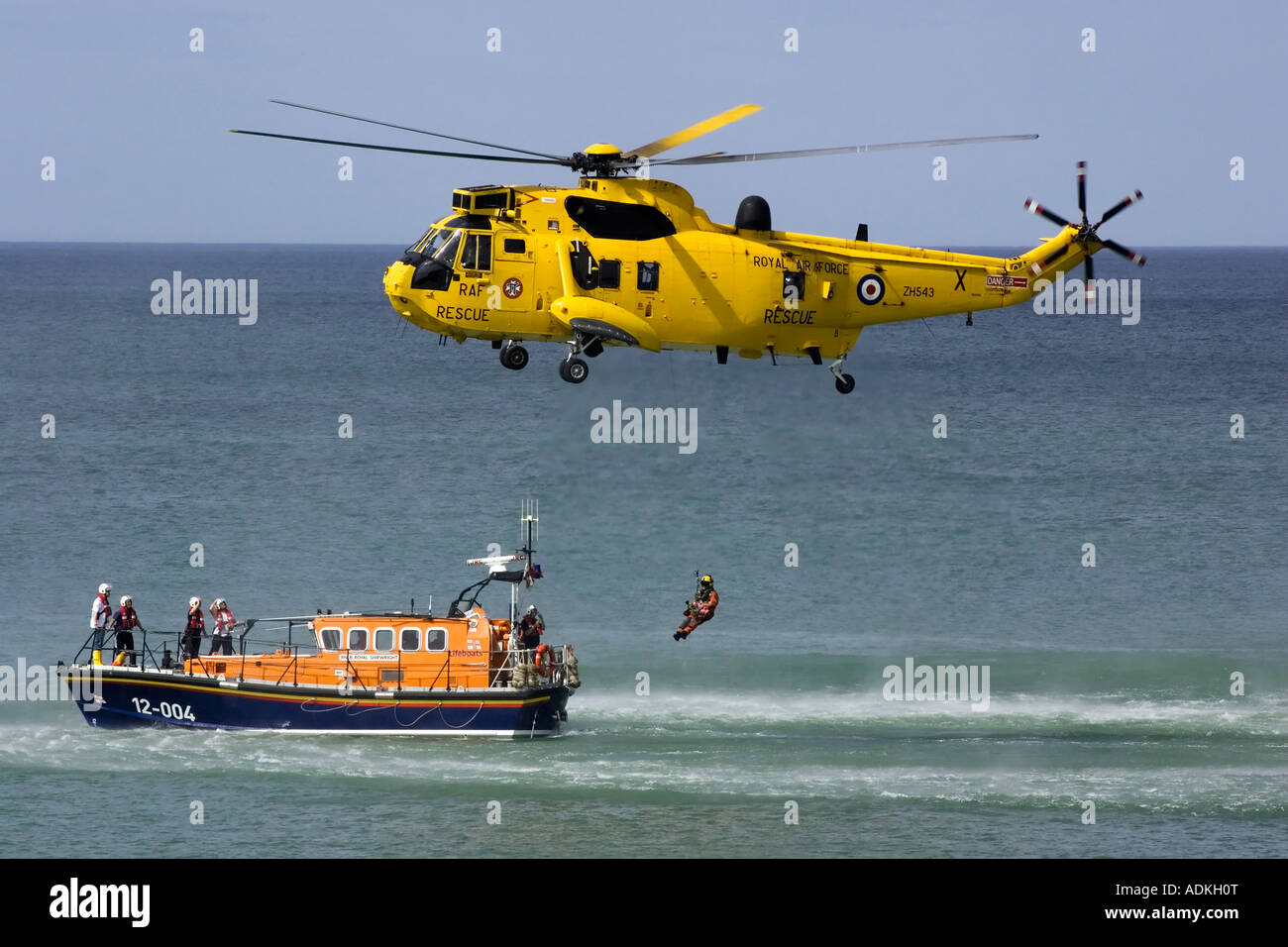An RAF Sea King rescue helicopter winching a crewman on to the deck of the Cromer RNLI mersey class lifeboat Stock Photo