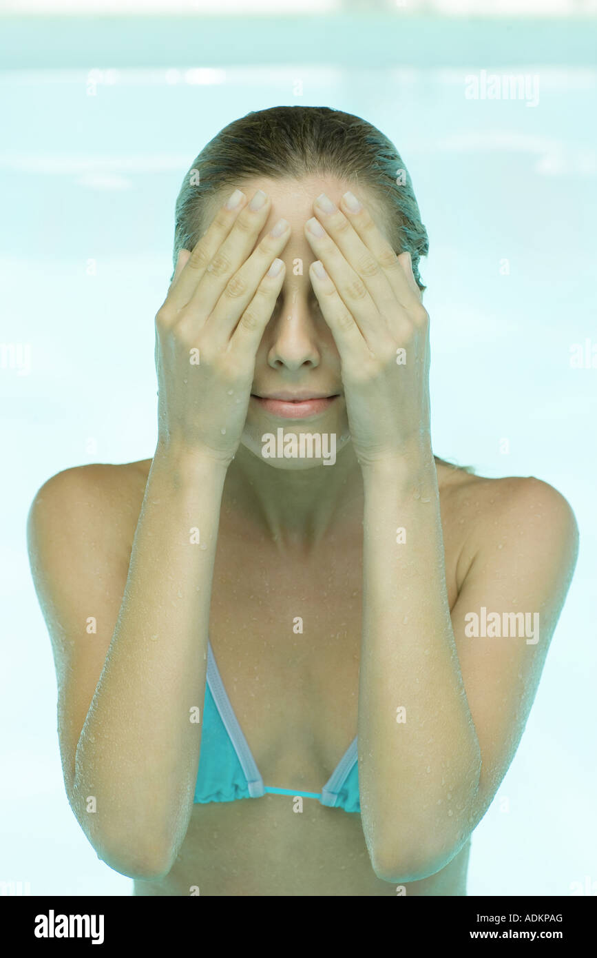 Young woman in swimsuit, hands over face Stock Photo