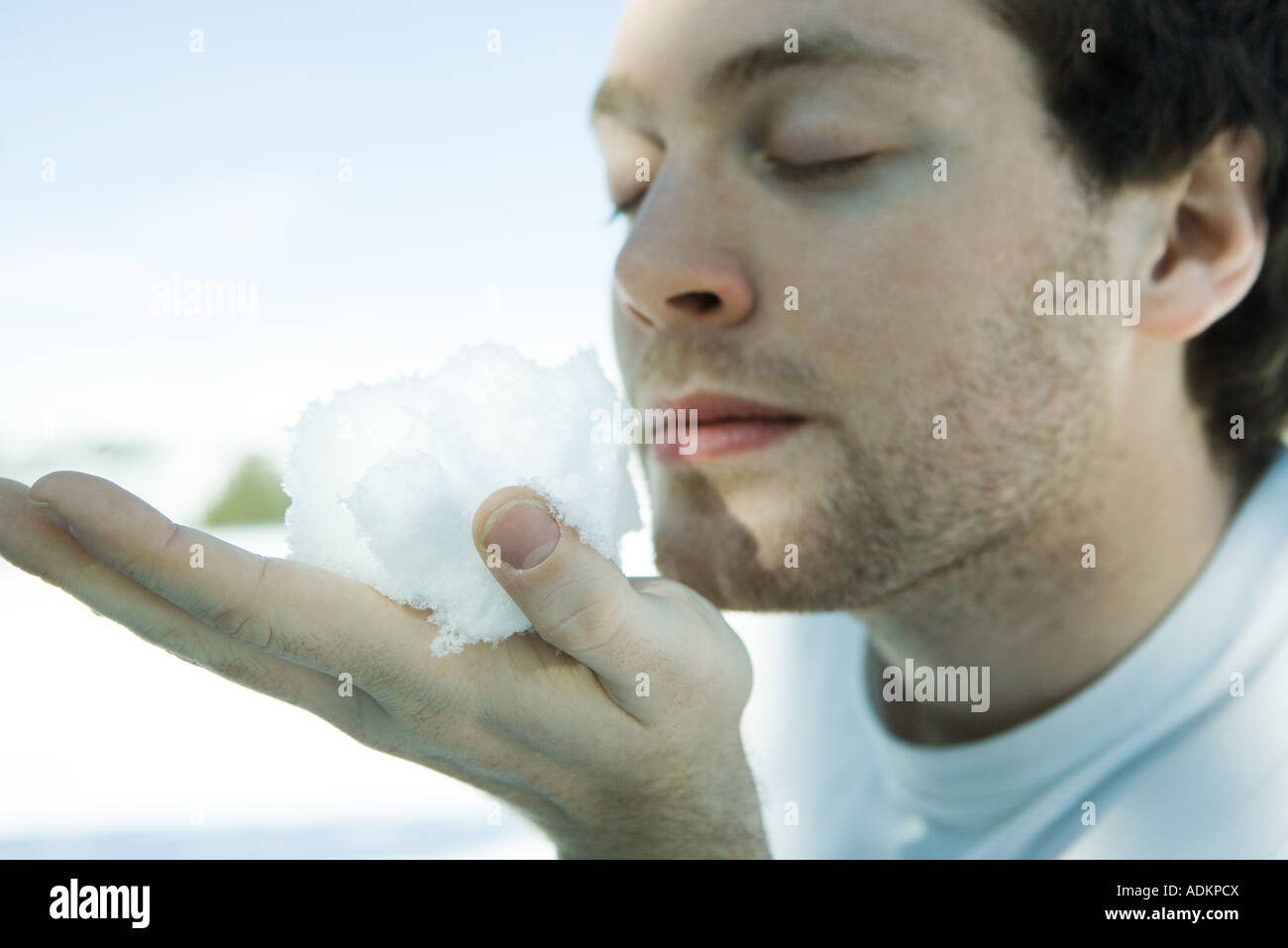 Young man holding snow ball in hand, eyes closed Stock Photo