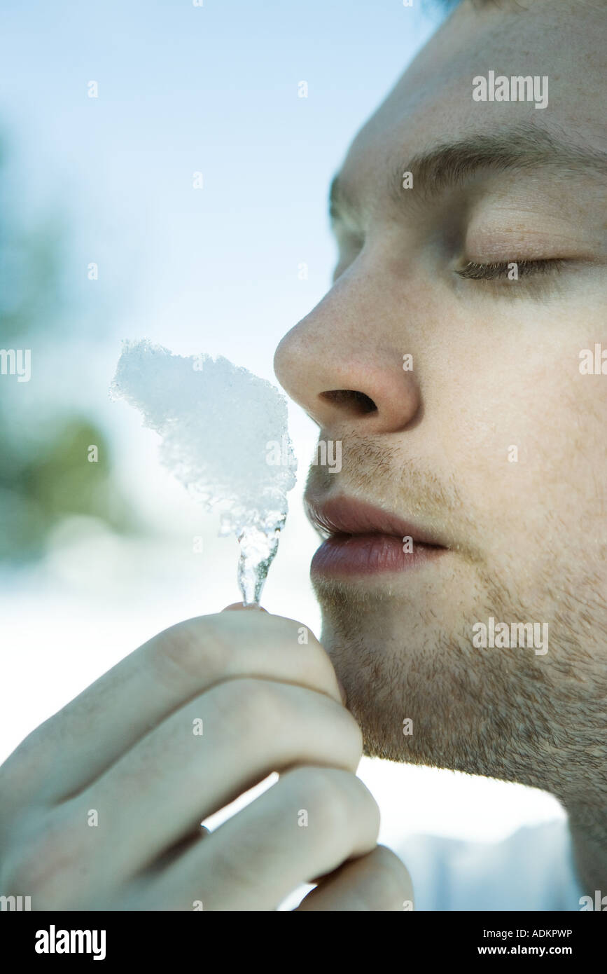 Young man smelling piece of snow, eyes closed Stock Photo