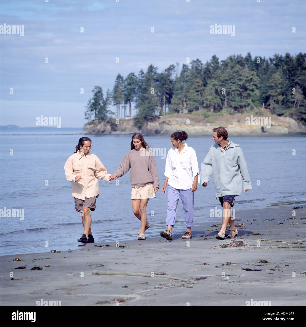 Two Couples Walking Along A Beach Stock Photo - Alamy