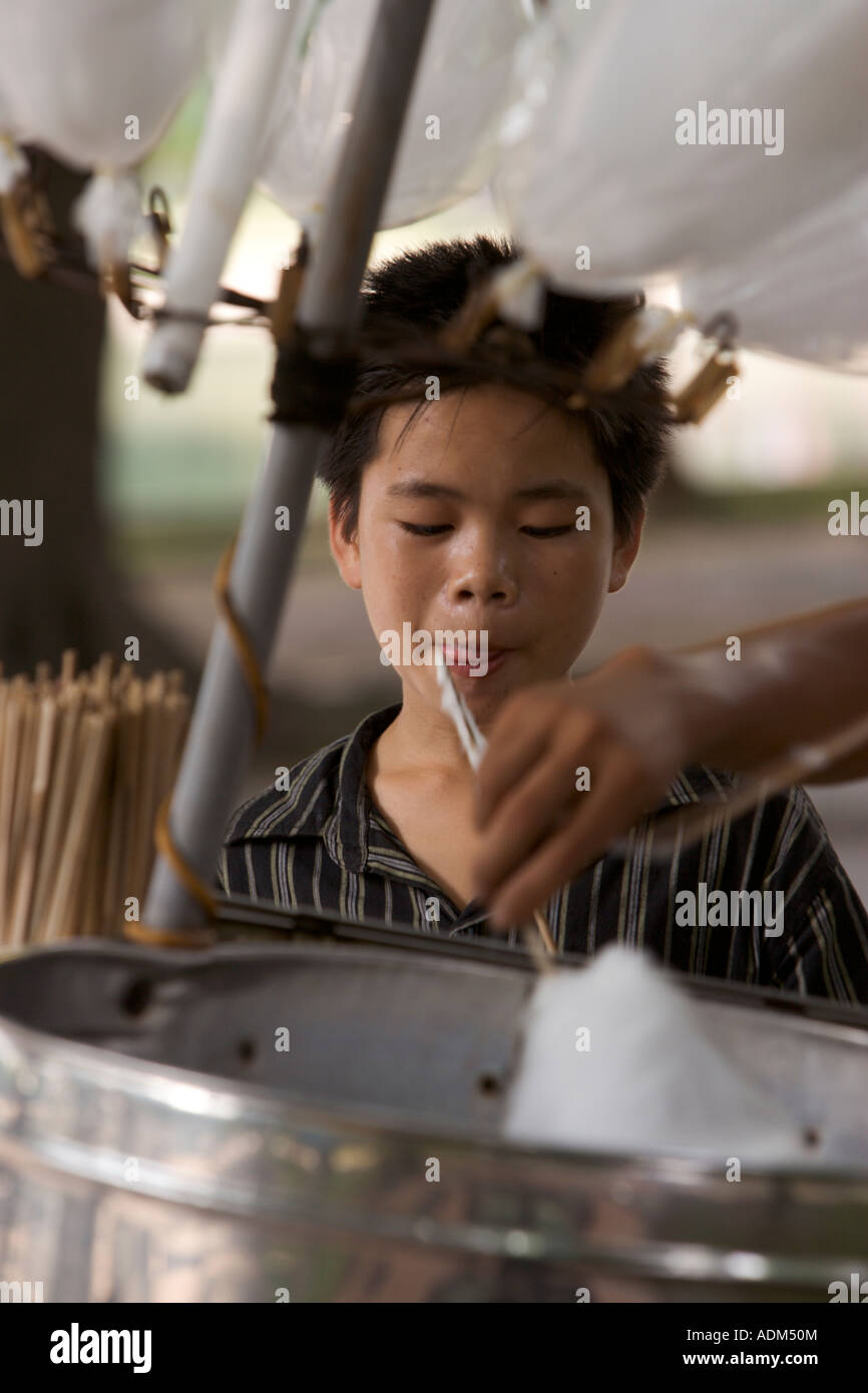 Young Vietnamese boy licks his lips while staring at a cotton candy bin