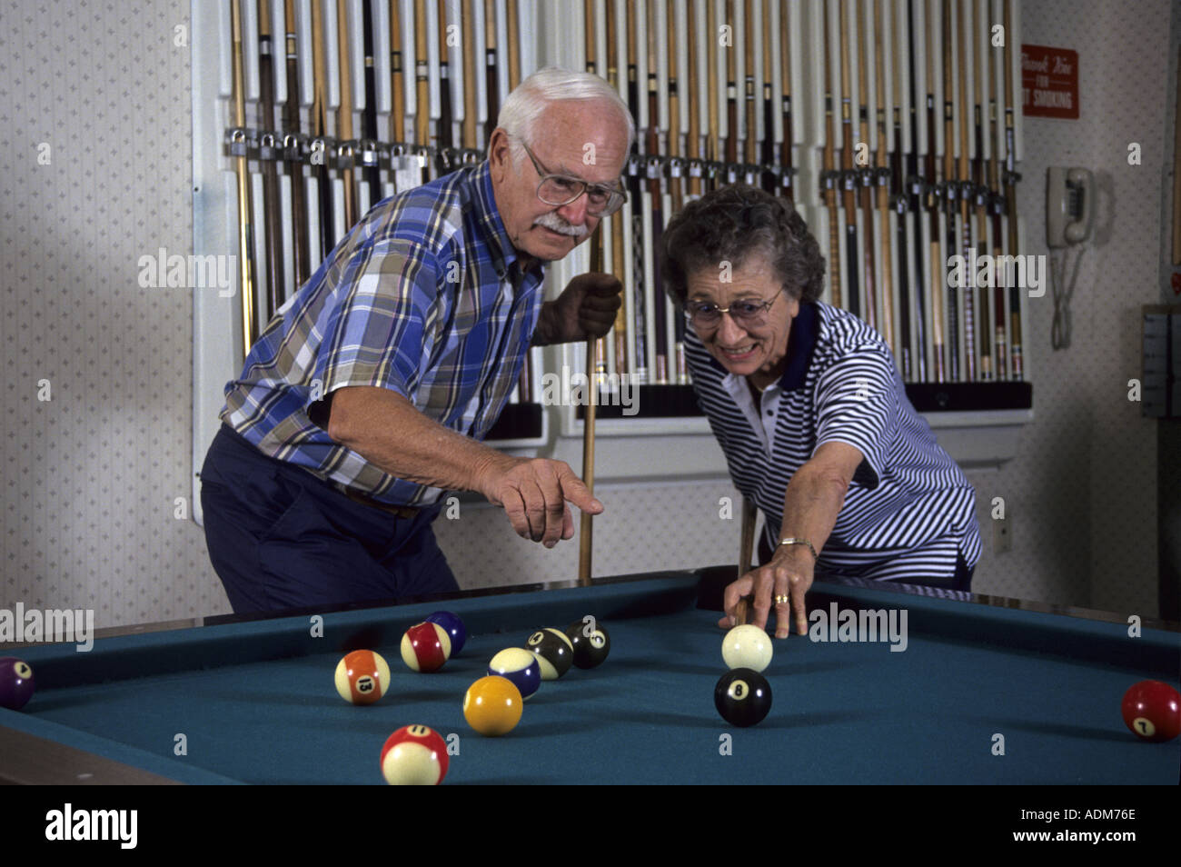 Young at heart Happy teasing Socially Active social Senior couple citizens fun playing pool billiard billiards room of retirement home America MR  © Myrleen Pearson Stock Photo