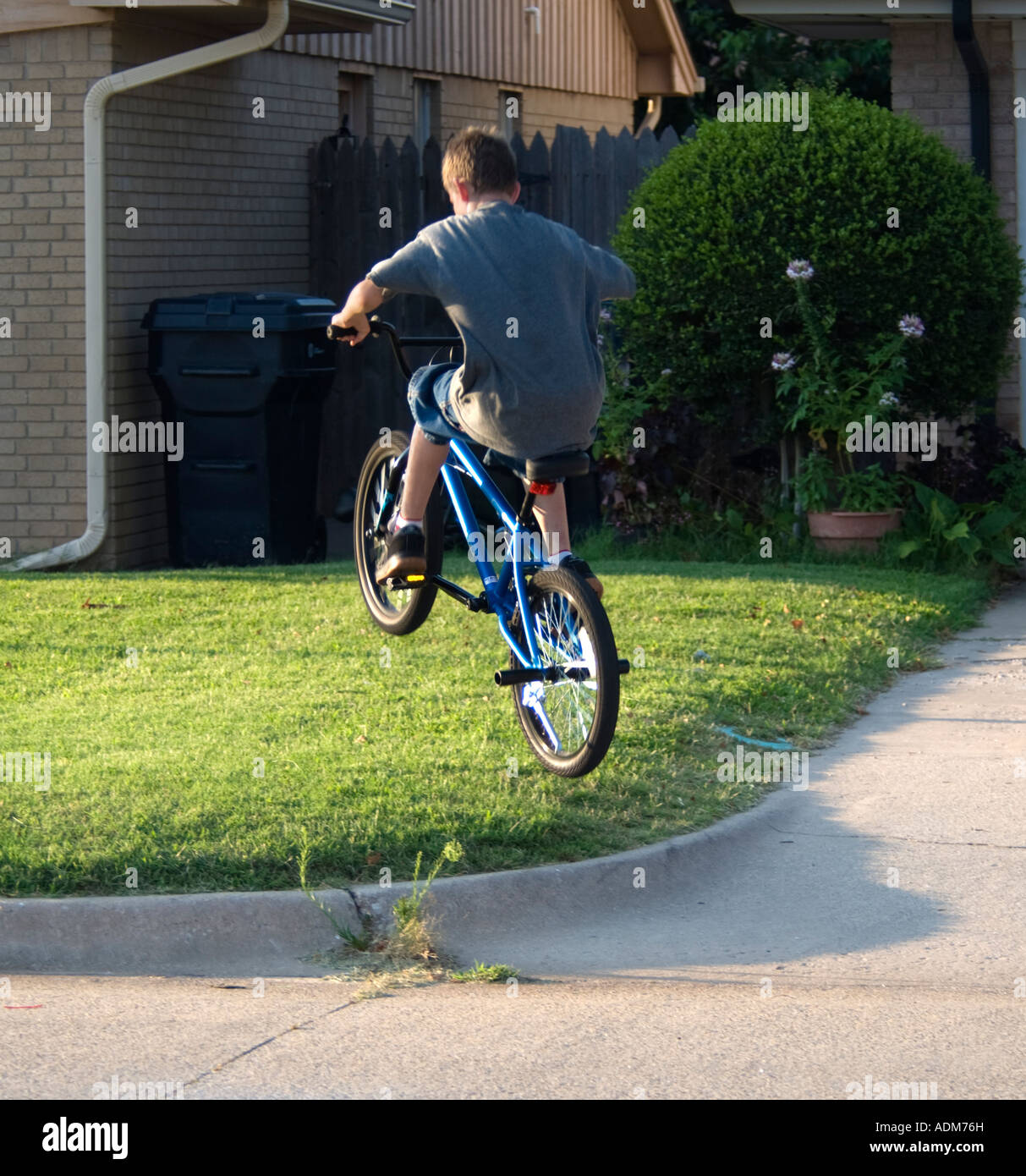 A teenage caucasian boy jumps curb on his bicycle. Oklahoma City